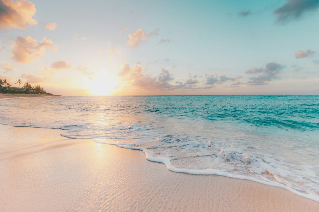 Plage de sable fin au coucher du soleil avec vagues turquoise